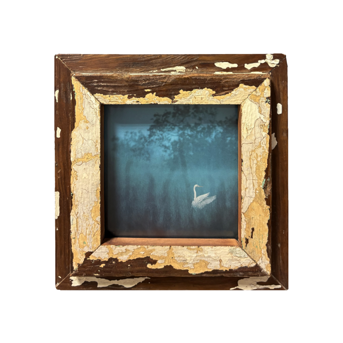 L'Ora in cui il Mondo Tace: fotografia blue hour con airone bianco su stagno nebbioso e luce gialla sullo sfondo, cornice quadrata in legno recuperato marrone con vernice avorio scrostata, stile Wabi-Sabi, 23×23 cm.