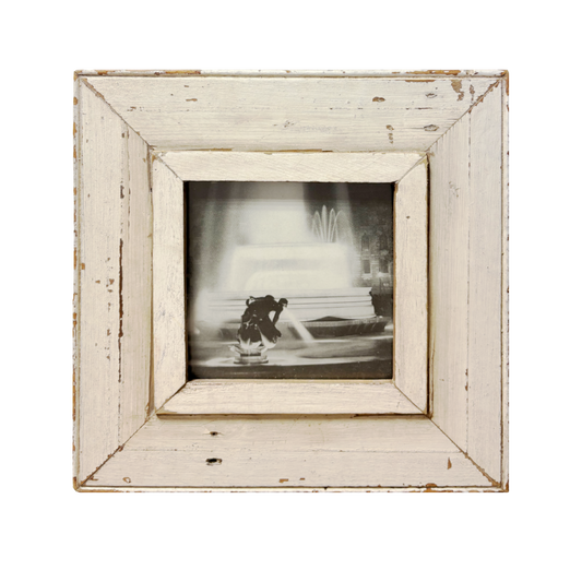 Fotografia bianco e nero "Notturno con Acqua" con cornice bianca vintage, sagoma di scultura in primo piano e fontana illuminata sullo sfondo con palazzo antico