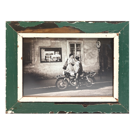 Cornice rettangolare verde imperiale 55×43 cm con passe-partout in legno bianco naturale e vernice erosa sui bordi, contenente fotografia B&W analogica di coppia su motocicletta Ducati/Moto Guzzi anni '80 in strada estiva italiana, lui guarda lei, lei guarda altrove, stile Classico italiano, legno recuperato Cape Town 