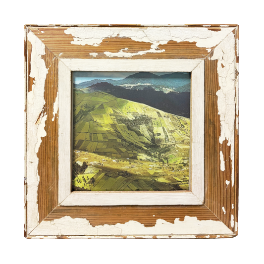 Cornice rustica in legno avorio scrostato con veduta aerea drone di colline verdi, profili neri e cielo azzurro — arredo paesaggistico 34x34 cm 