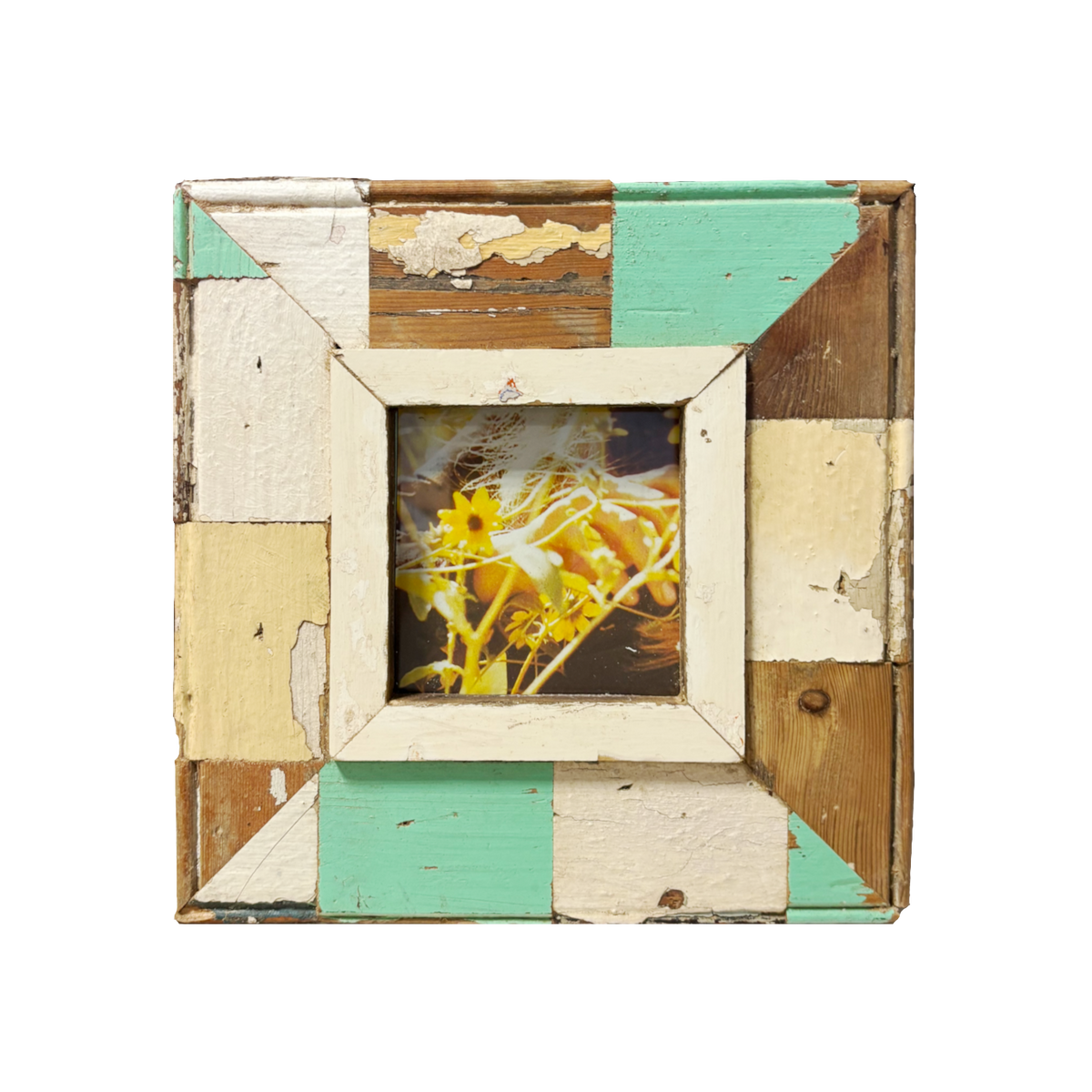 Girasole giovane con dettagli botanici nitidi, circondato da elementi floreali gialli sfocati; cornice rustica mosaico multicolor (crema, verde, marrone) con passe-partout avorio, 24×24 cm 