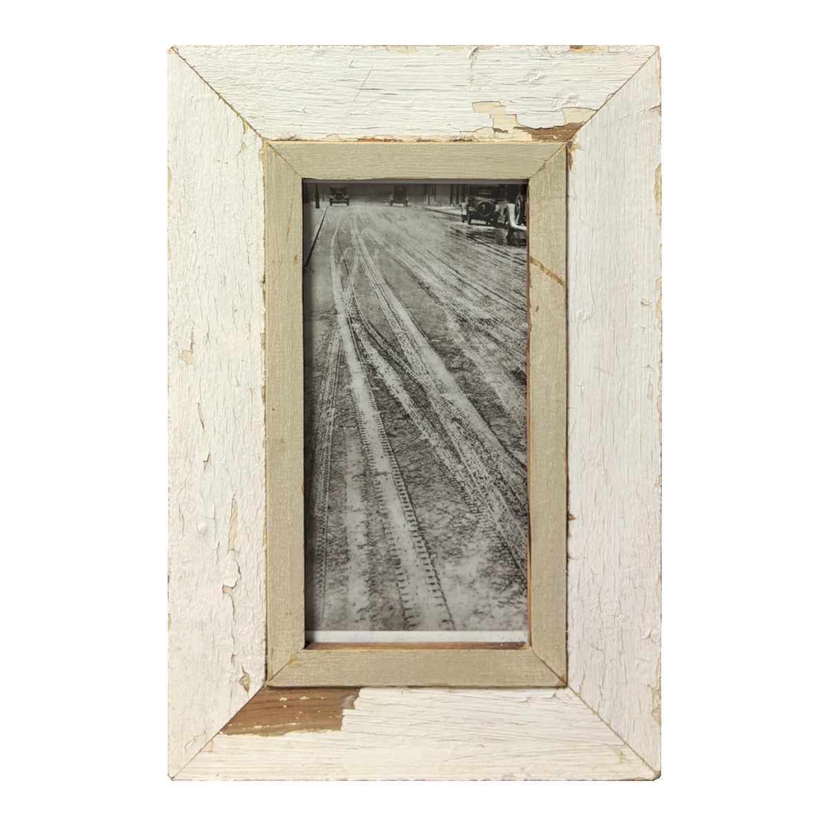 Fotografia minimalista in bianco e nero di tracce di pneumatici su strada fangosa, racchiusa in cornice di legno bianco sporco scrostato con passe-partout greige, stile minimalista.